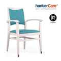 Chaise empilable pour seniors avec accoudoirs DENISE EMP TP CB RD001 avec un revêtement en tissu facile à entretenir et des roulettes sur deux pieds de chaise.